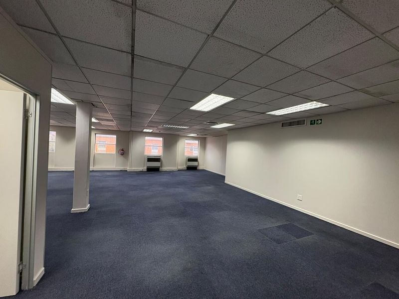 A spacious, open-plan office area featuring a suspended ceiling, recessed lighting, and carpeted flooring, ready for custom fit-out.