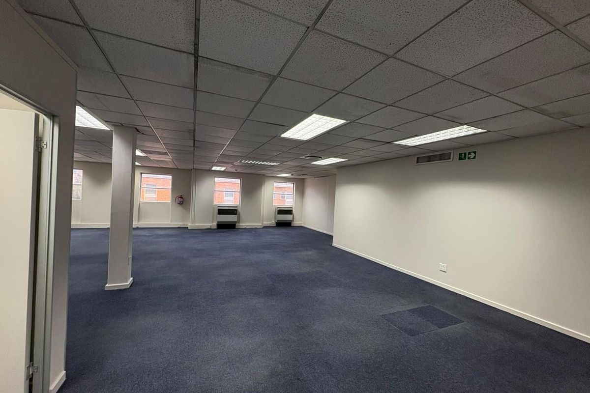 A spacious, open-plan office area featuring a suspended ceiling, recessed lighting, and carpeted flooring, ready for custom fit-out.
