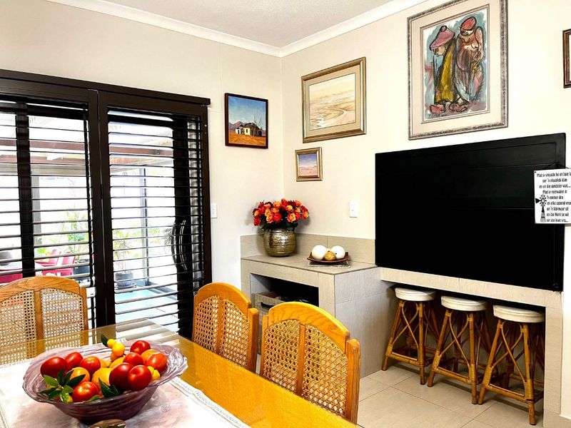 Living area featuring a built-in bar, tiled flooring, and sliding glass doors with plantation shutters leading to an outdoor space.