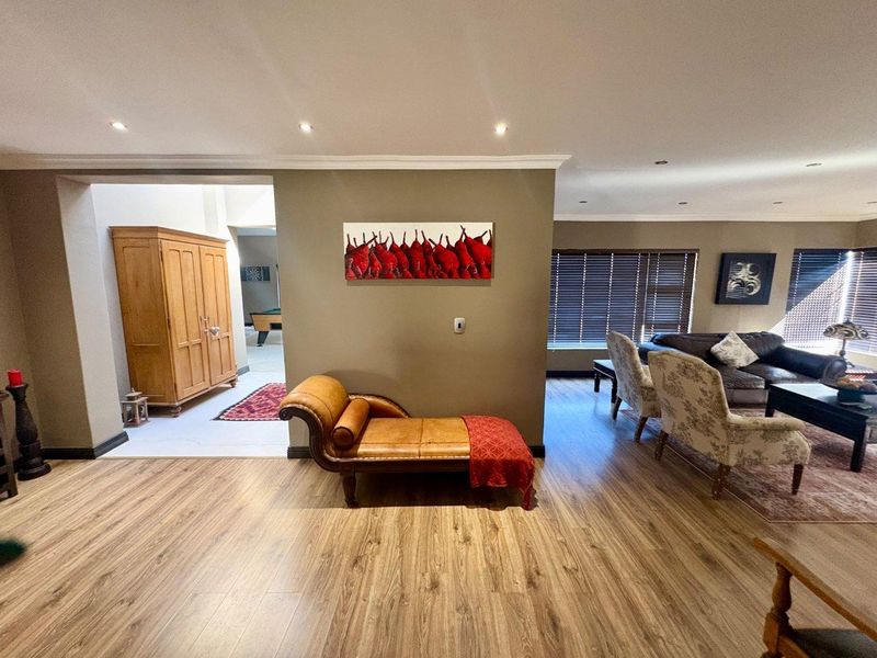 Spacious open-plan living area featuring laminate flooring, recessed downlighting, and large windows with venetian blinds, creating a bright and inviting atmosphere.