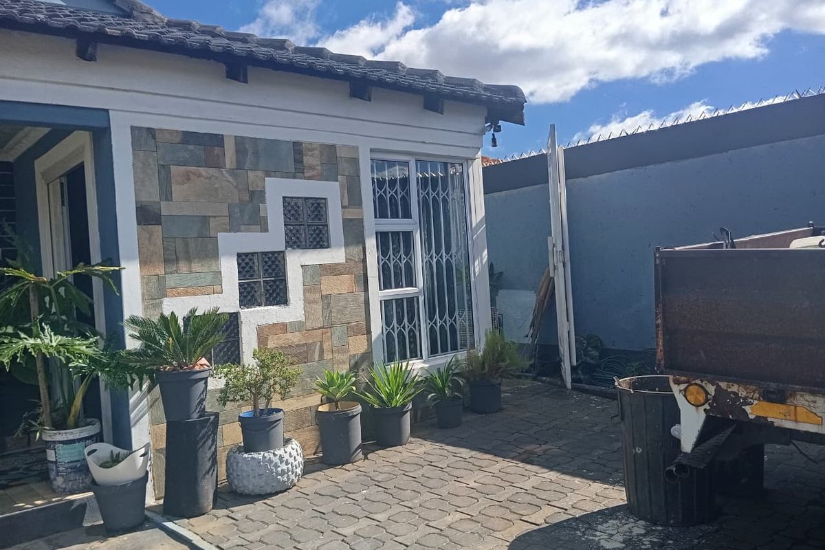Rear courtyard area featuring stone-clad exterior walls, glass block accents, security gates, and paved flooring.
