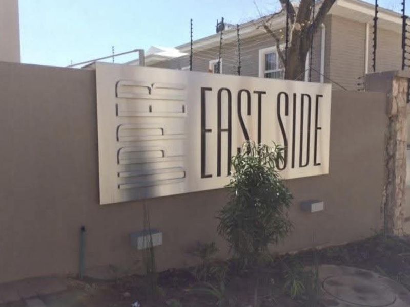 Exterior view of the apartment complex boundary wall featuring the Upper East Side signage and integrated security electric fencing.