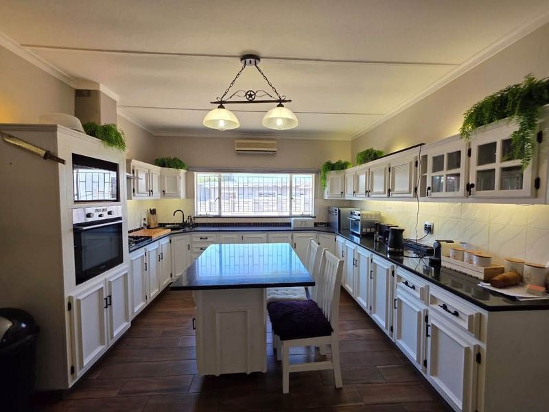 Spacious kitchen featuring white cabinetry, dark granite countertops, a central island, built-in oven and microwave, and tiled flooring.