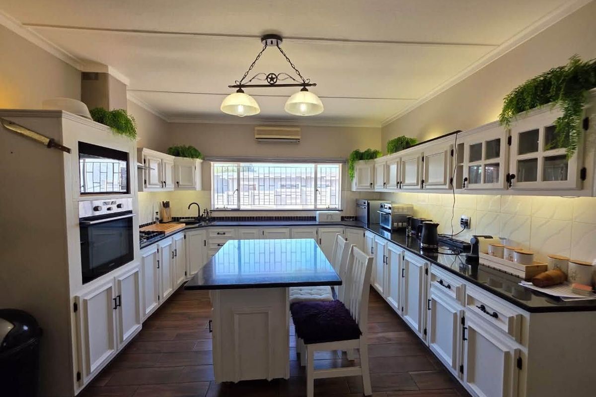 Spacious kitchen featuring white cabinetry, dark granite countertops, a central island, built-in oven and microwave, and tiled flooring.