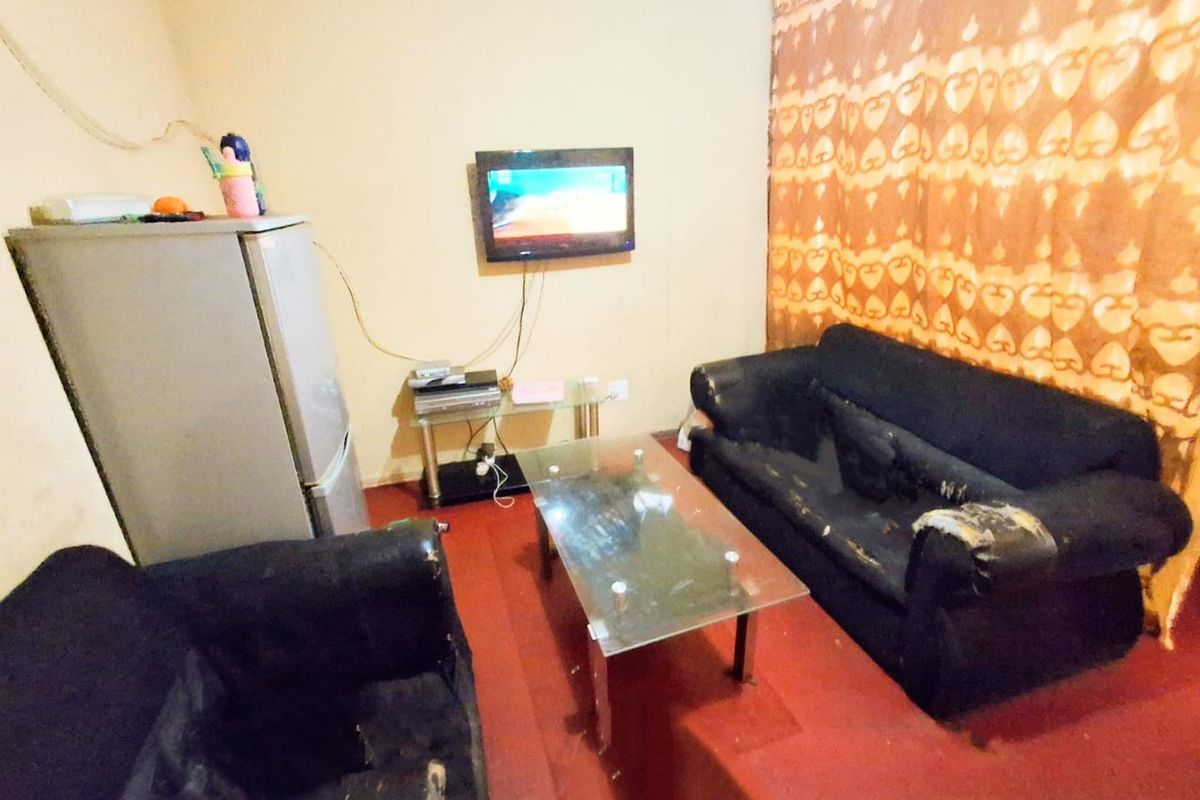 A compact living room area featuring tiled flooring and wall-mounted television space.