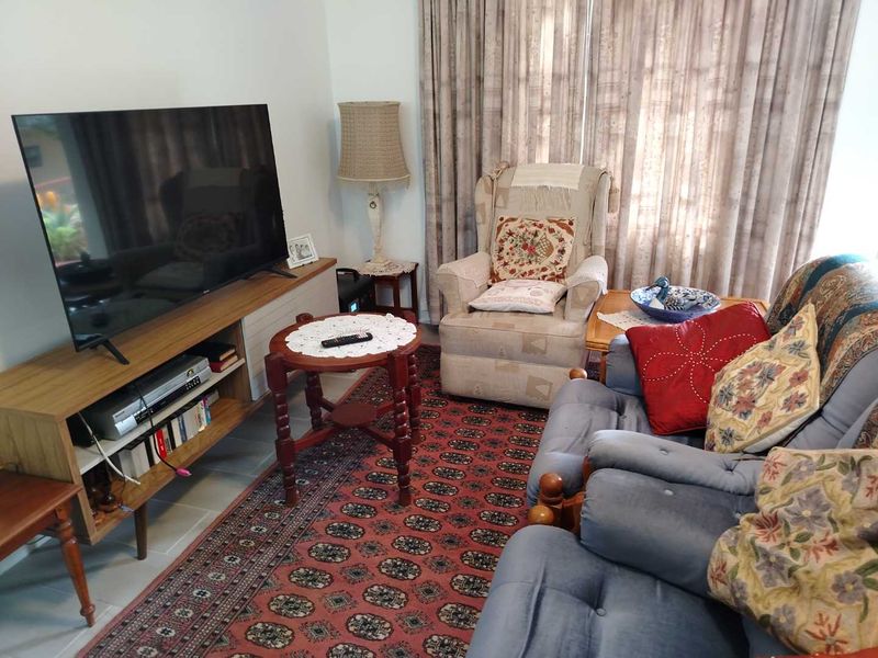 A comfortable living room area featuring tiled flooring and large window curtains, providing a functional space for relaxation.