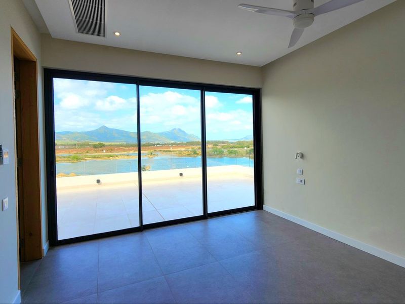 Spacious bedroom featuring large sliding glass doors that open onto a private terrace with scenic water and mountain views.