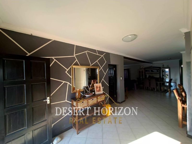 Entrance hall featuring tiled flooring and a decorative accent wall, leading into an open-plan living and dining area.