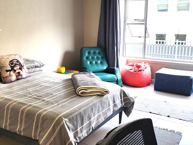 A bedroom featuring tiled flooring and a large window that provides natural light.