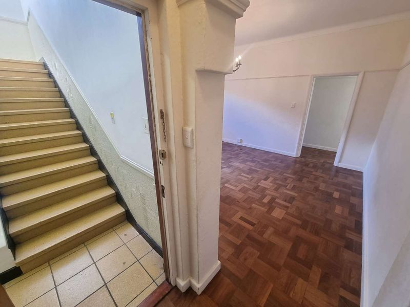Entrance area featuring classic parquet flooring, a tiled staircase, and a structural archway leading into the main living space.