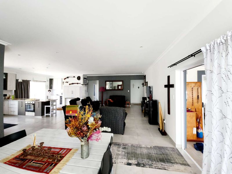 Spacious open-plan living area featuring a modern kitchen with built-in appliances, tiled flooring throughout, and seamless flow to an adjacent room.