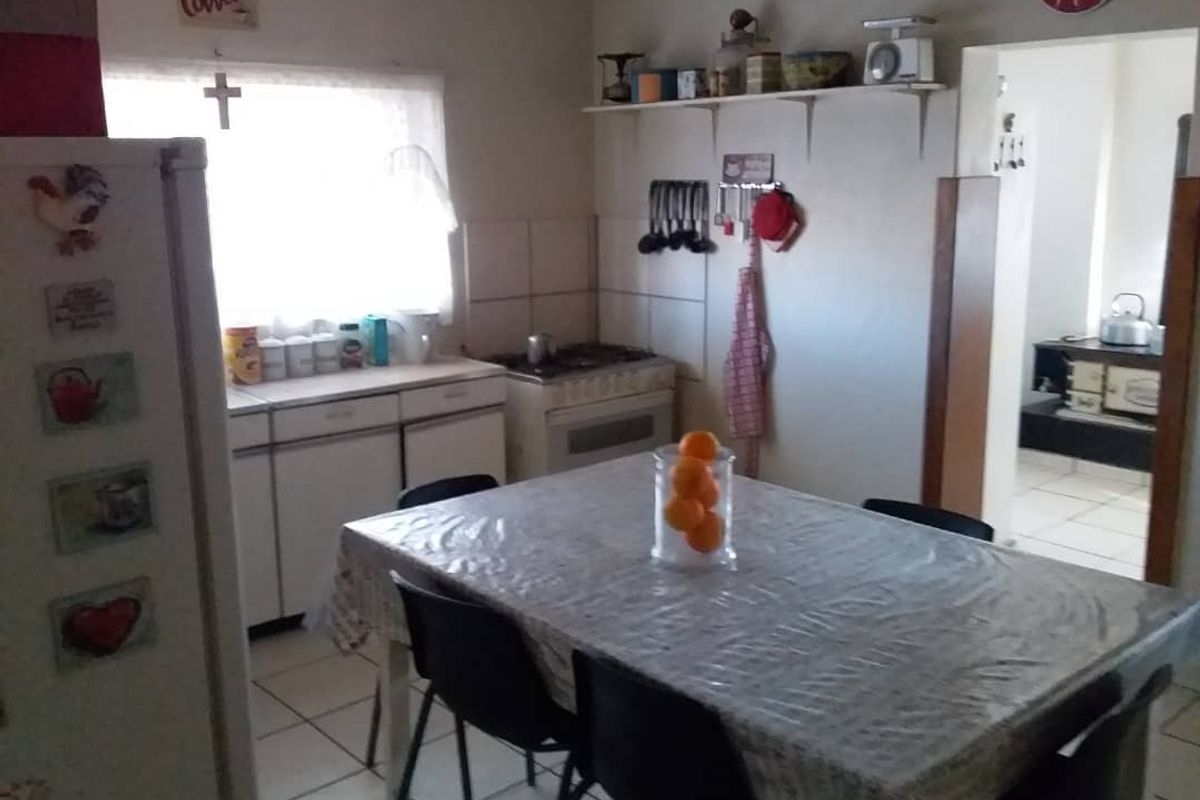 A functional kitchen area featuring basic cabinetry, a freestanding stove, and tiled flooring, with an adjacent dining space.