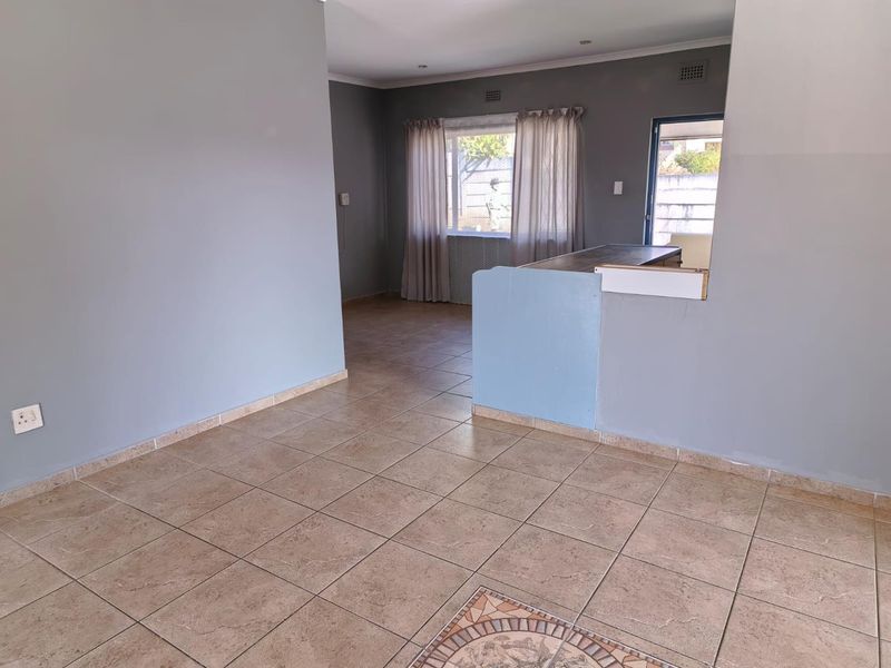 An open-plan living area featuring tiled flooring and a breakfast bar, offering a versatile space ready for personalization.