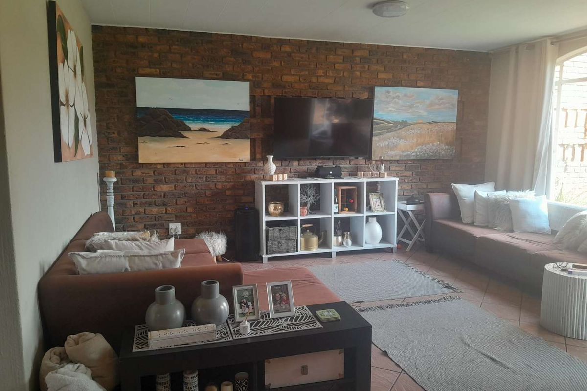 A cozy living room featuring an exposed brick feature wall and tiled flooring, providing a warm and textured aesthetic.