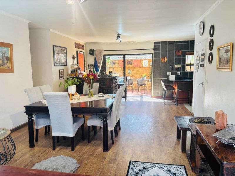 Spacious open-plan living and dining area featuring laminate flooring, a built-in breakfast bar, and sliding glass doors leading to an outdoor patio.