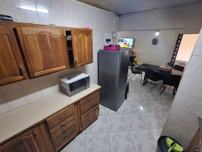Open plan kitchen and dining area featuring wooden cabinetry, tiled backsplash, and tiled flooring, offering a functional layout for daily living.