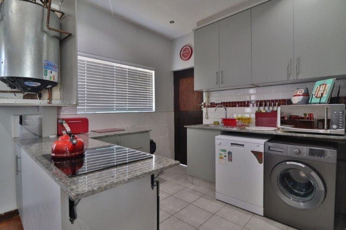 Functional kitchen featuring granite countertops, grey cabinetry, tiled flooring, and integrated space for laundry appliances.
