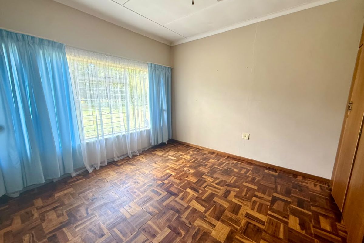 A vacant bedroom featuring classic parquet flooring, a ceiling fan, and built-in storage, offering a blank canvas for personalization.