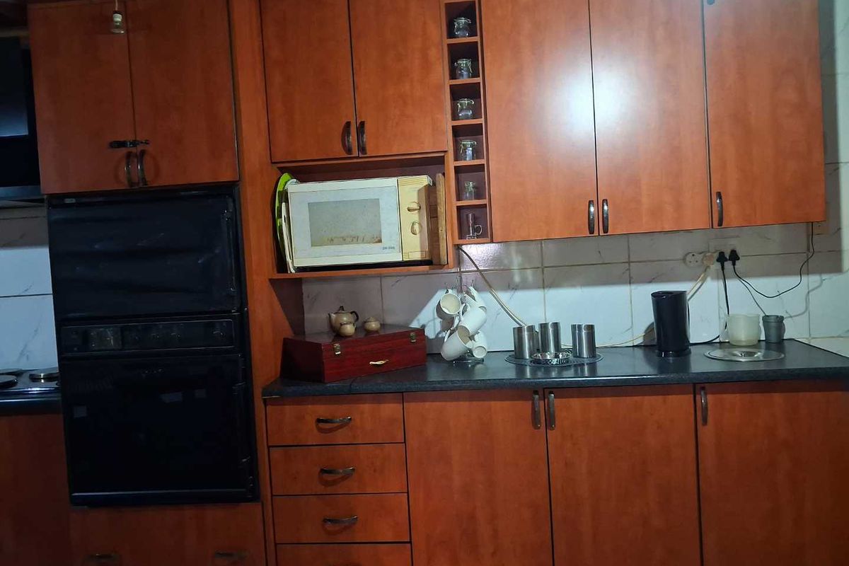 A functional kitchen featuring wood-tone cabinetry, built-in oven, and dark laminate countertops, providing ample storage and workspace for daily meal preparation.
