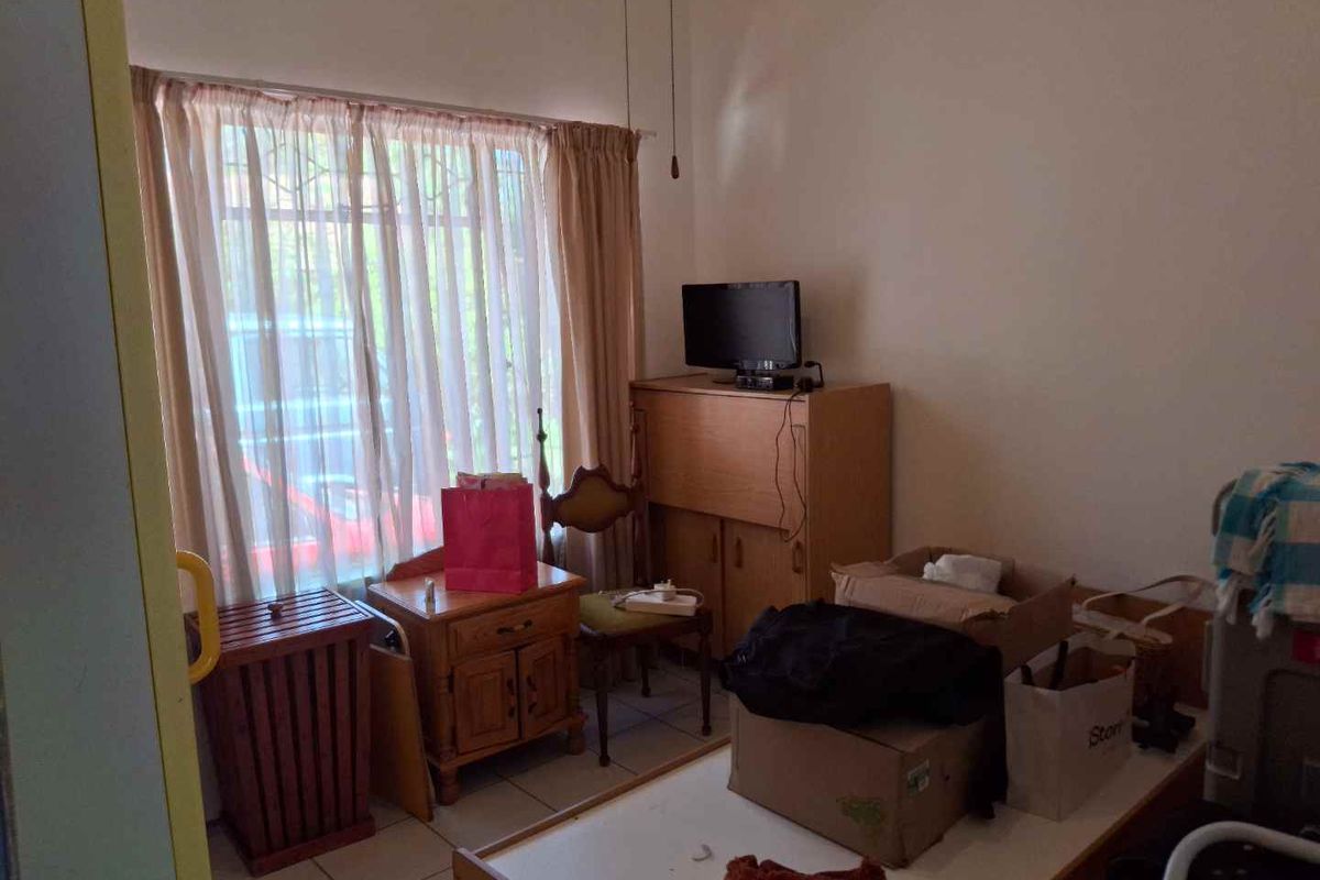 A bedroom featuring tiled flooring and a large window with curtain rails, offering a functional space ready for modernization.