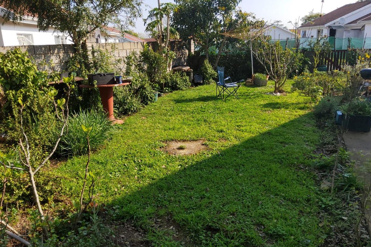 A private rear garden featuring a lawn area, paved walkway, and concrete block boundary walls.
