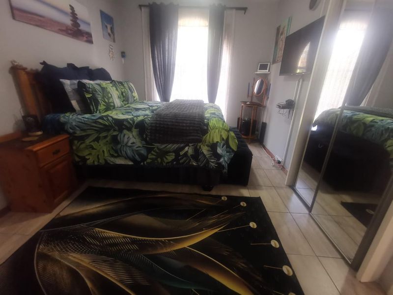 A bedroom featuring tiled flooring and a built-in wardrobe with mirrored sliding doors, providing functional storage space.