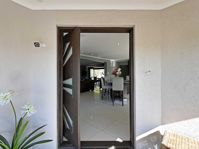 View through the modern front entrance into an open-plan living and dining area with tiled flooring and recessed lighting.
