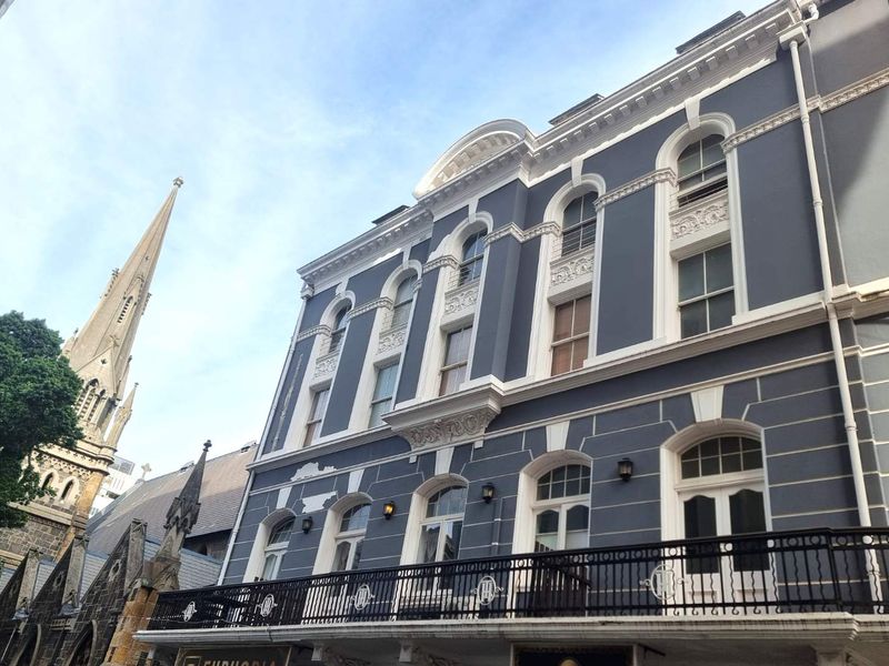 A historic apartment building facade featuring ornate architectural detailing, arched windows, and a classic wrought iron balcony.