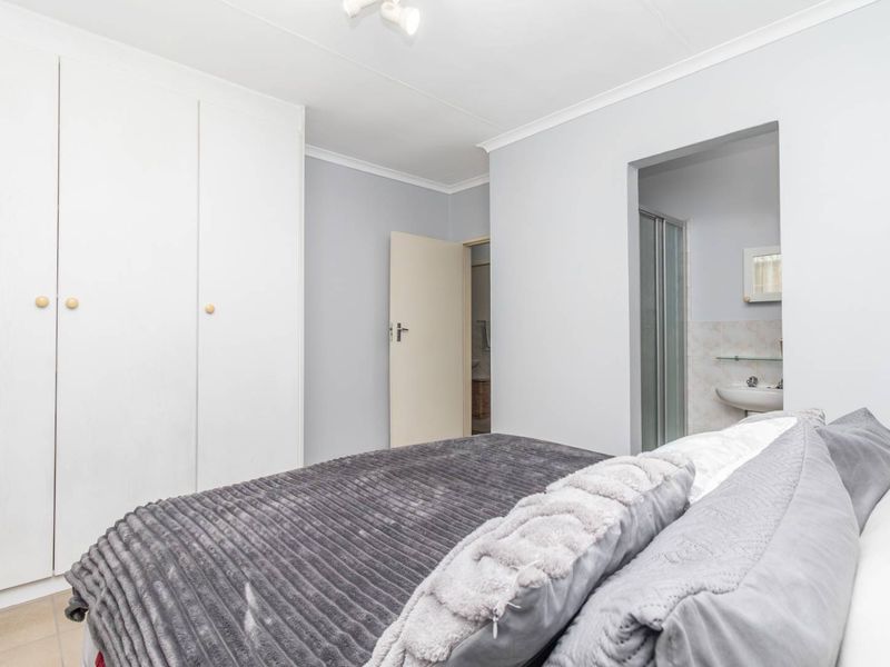 A bedroom featuring built-in cupboards and an en-suite bathroom with a shower and basin.