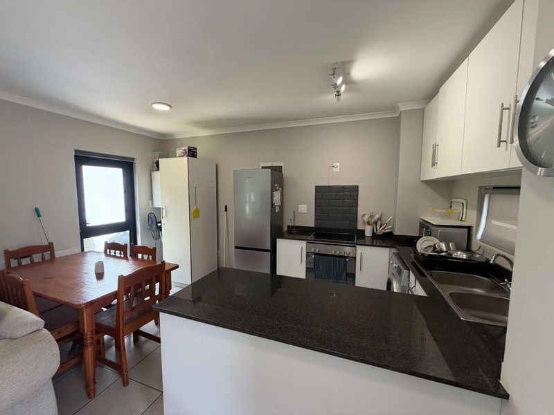 Open-plan kitchen and dining area featuring granite countertops, modern cabinetry, built-in appliances, and tiled flooring, creating a functional and cohesive living space.