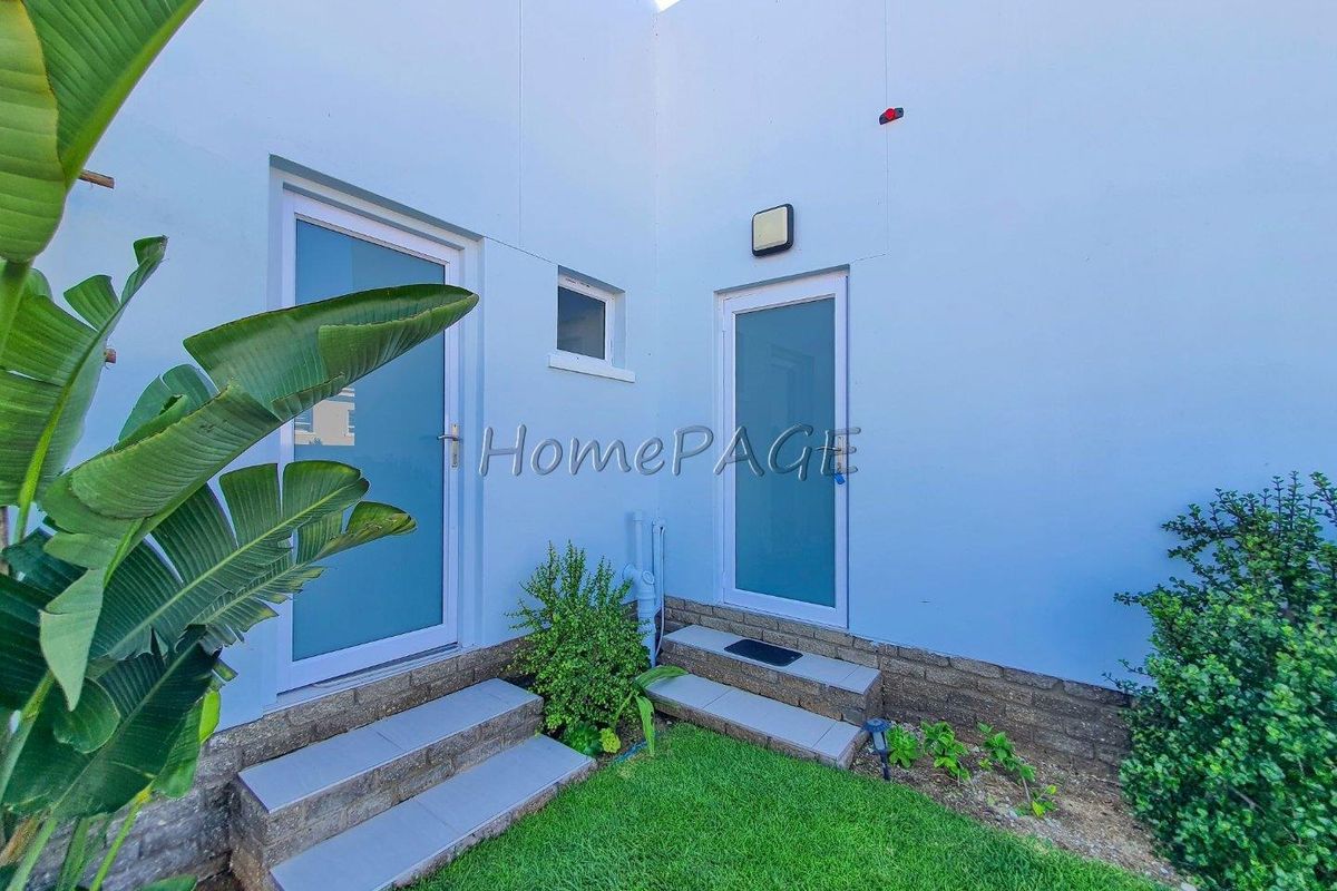 A private courtyard area featuring two glass-panelled doors, tiled steps, and a small patch of lawn.