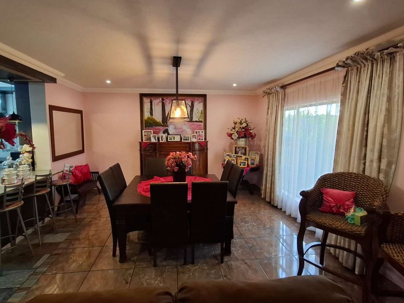 Open plan dining and kitchen area featuring tiled flooring, recessed lighting, and a breakfast bar, with direct access to the outdoors via sliding glass doors.