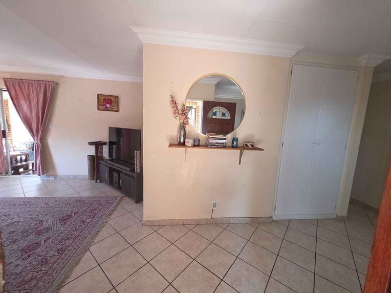 A living area featuring tiled flooring, coving, and a built-in storage cupboard, providing a functional and neutral space.
