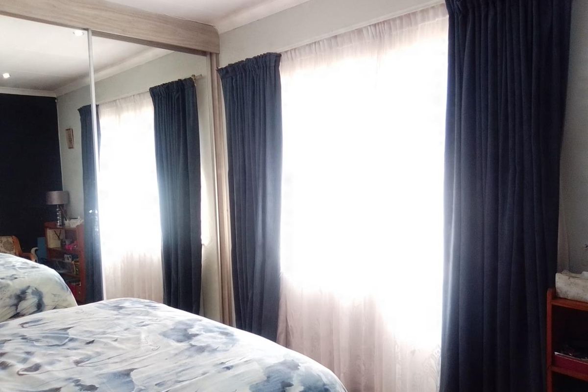 A bedroom featuring a large built-in mirrored wardrobe and classic cove cornicing, providing ample storage and a bright, airy feel.