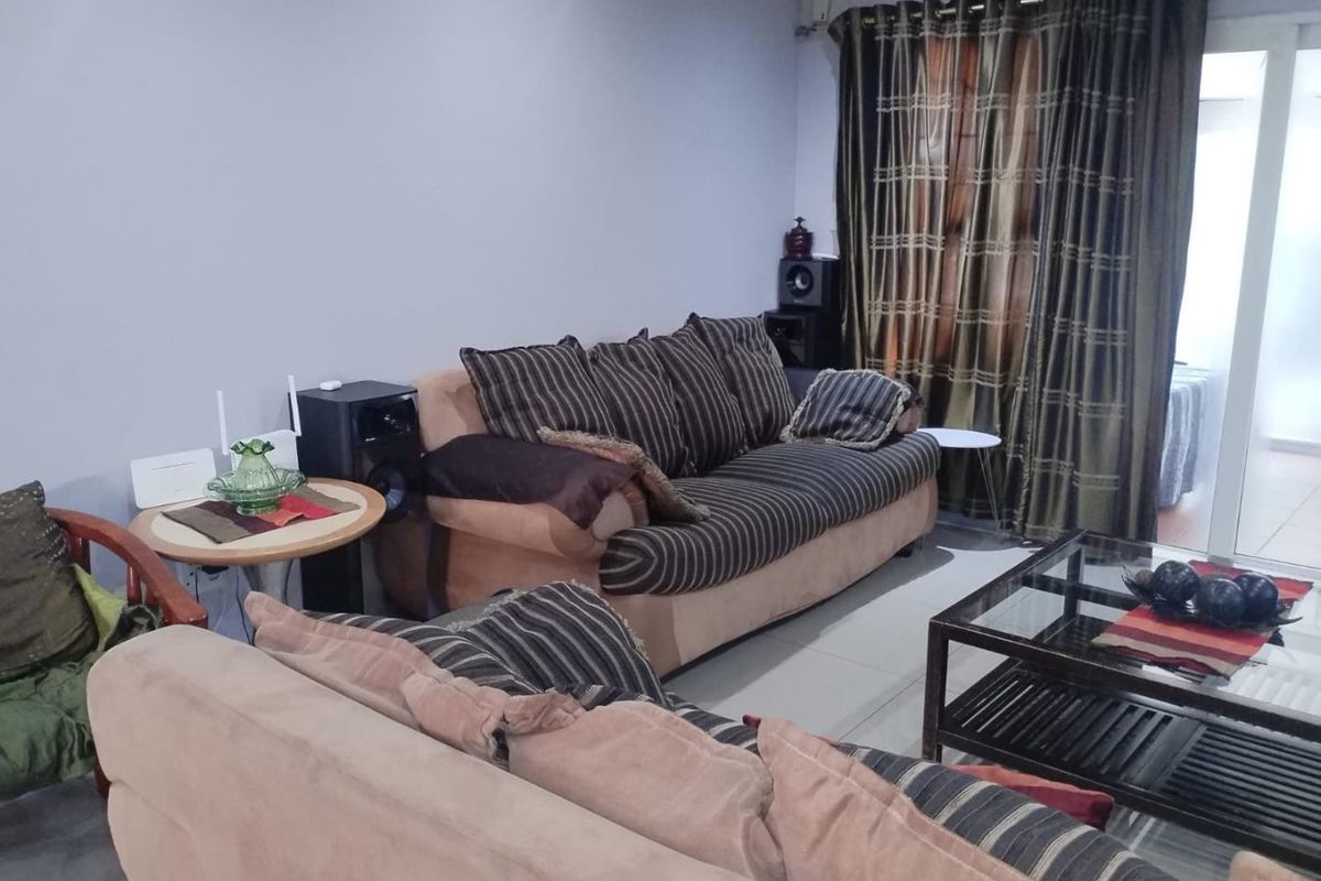 A comfortable living room featuring tiled flooring and a sliding glass door providing access to the exterior.