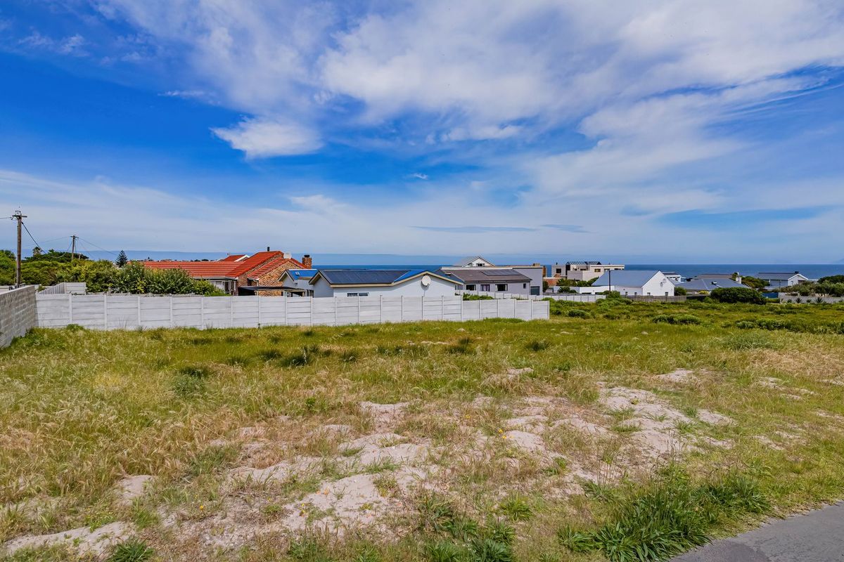 A vacant residential plot featuring a precast concrete boundary wall, offering a clear view of the surrounding neighborhood and distant coastal horizon.