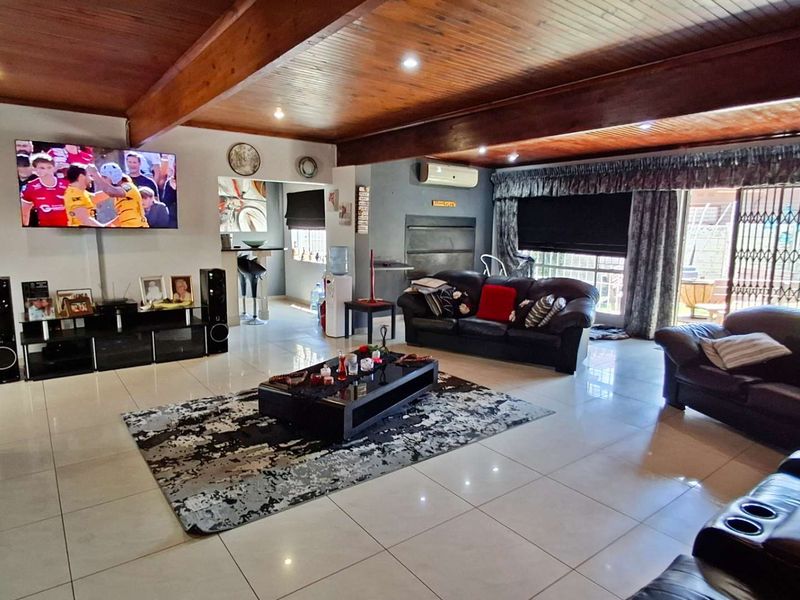 Spacious living area featuring exposed timber ceiling beams, tiled flooring, and direct access to the outdoor area through sliding glass doors.