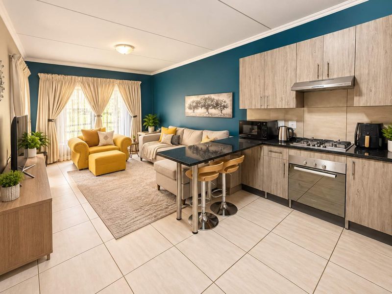 A well-maintained open-plan living area featuring a modern kitchen with granite countertops, built-in oven, gas hob, and tiled flooring throughout.