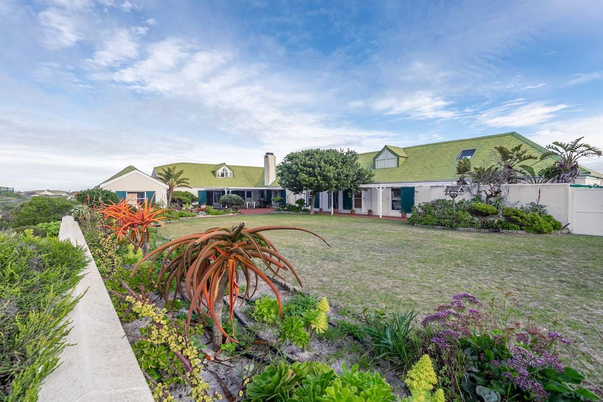 Spacious rear garden and lawn area featuring a well-maintained house exterior with green roof tiles and a covered patio.