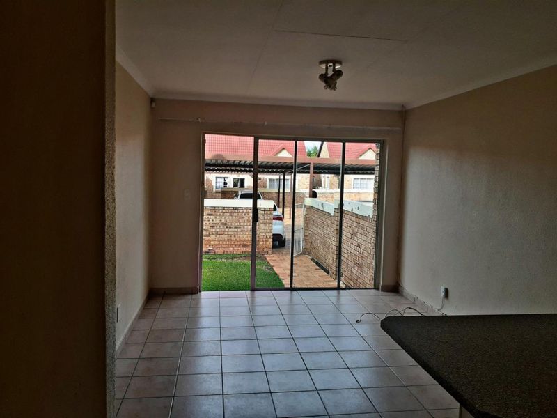 An empty living room featuring tiled flooring and large sliding glass doors that provide access to the exterior area.