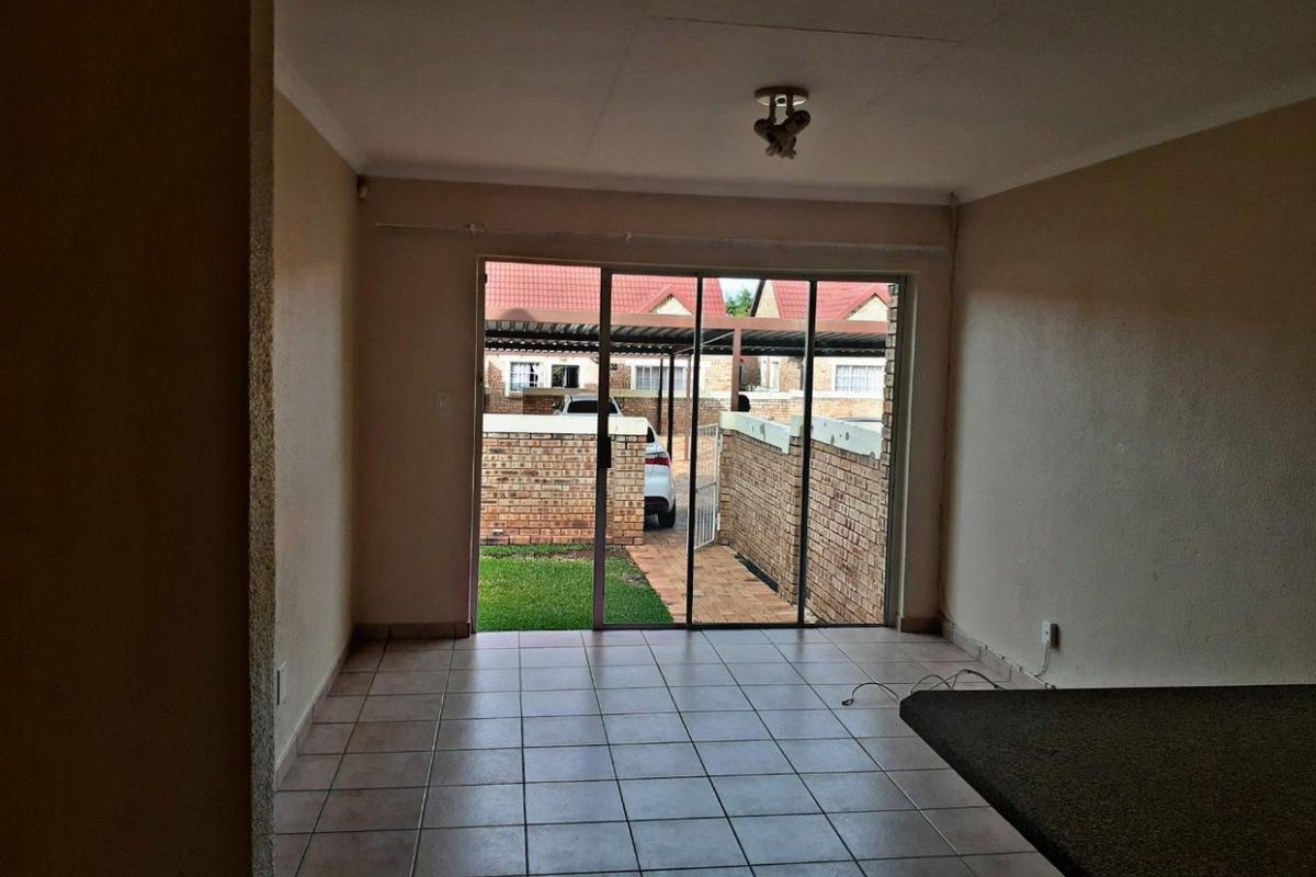 An empty living room featuring tiled flooring and large sliding glass doors that provide access to the exterior area.