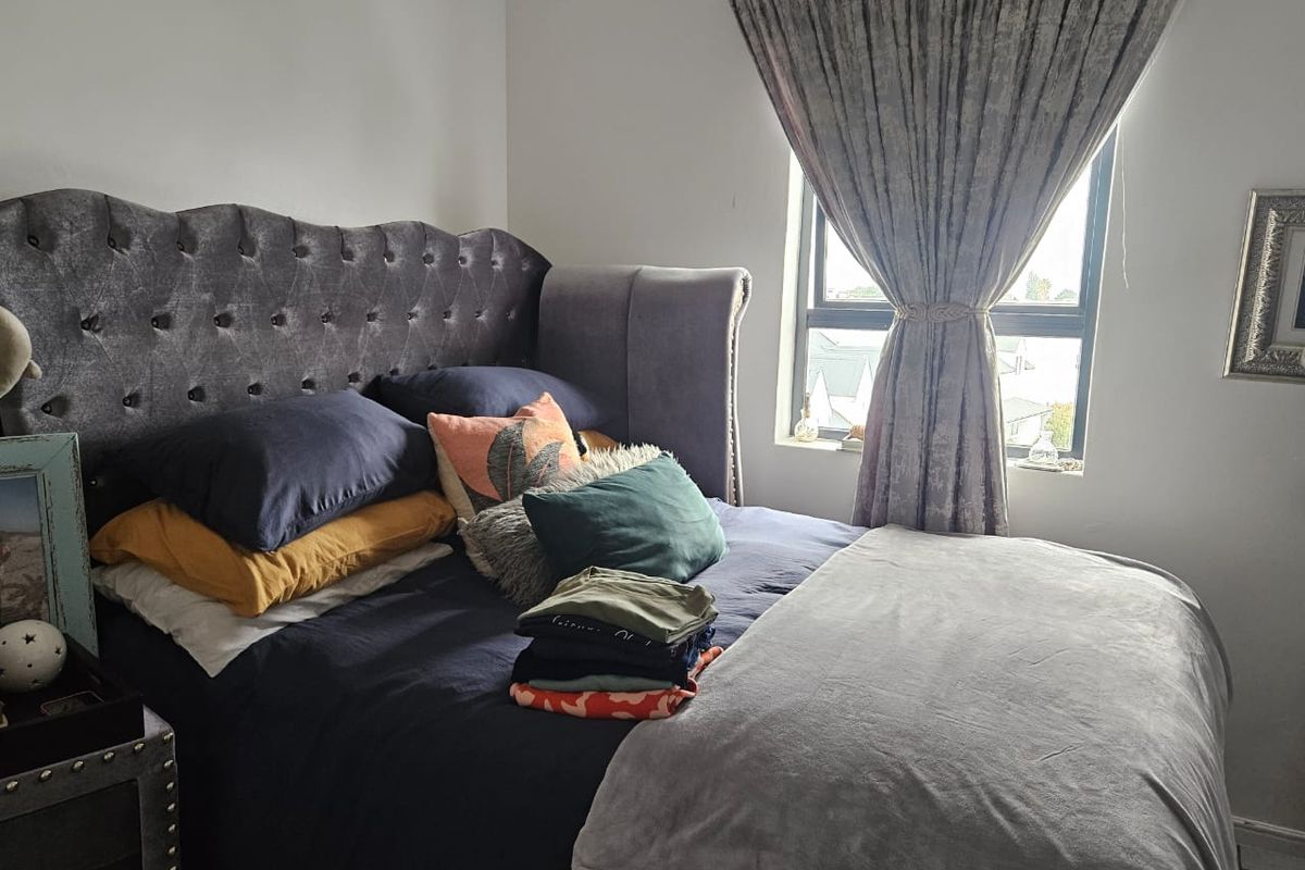 A bedroom featuring a window with aluminium frames and neutral wall finishes.