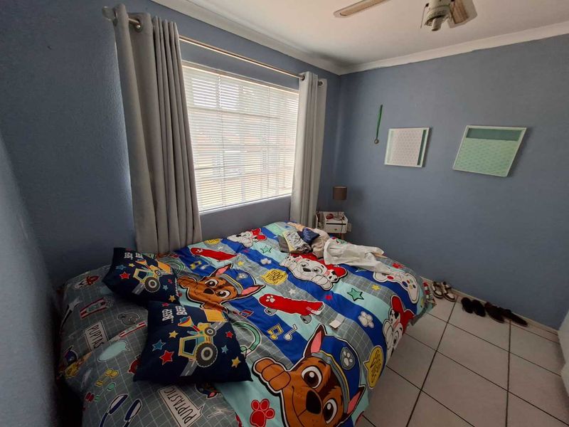 A standard bedroom featuring tiled flooring, a ceiling fan, and venetian blinds, providing a functional space ready for personalization.