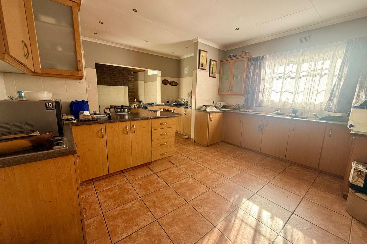 Spacious kitchen featuring wooden cabinetry, granite countertops, and tiled flooring, offering a functional layout with ample storage and preparation space.