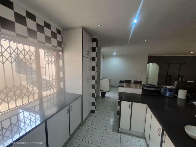 A functional kitchen featuring built-in cabinetry, dark stone countertops, and tiled flooring, with a security gate on the window.