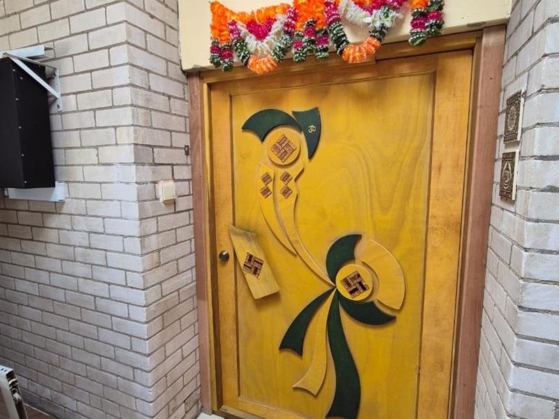 A residential entrance featuring a decorative wooden front door set within a light-colored brick facade.