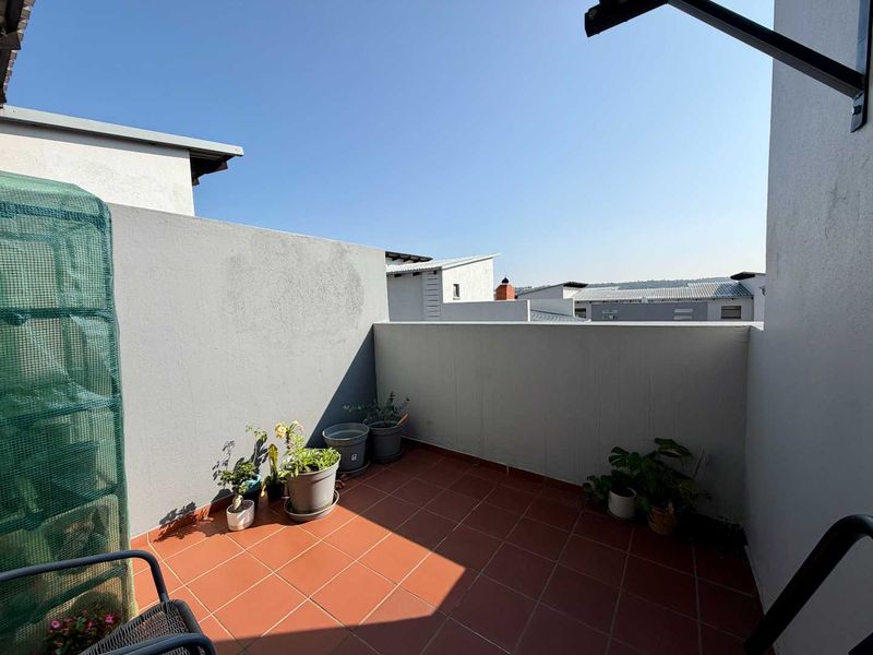 An open-air balcony featuring terracotta-style floor tiles and solid perimeter walls, offering a clear outdoor space for relaxation.