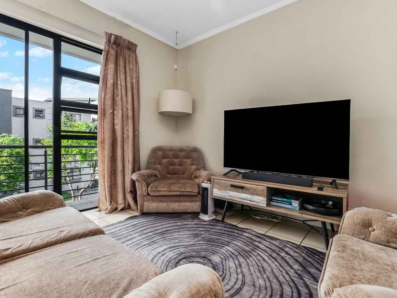 A comfortable living room featuring tiled flooring and a large sliding glass door that provides access to an outdoor balcony area.
