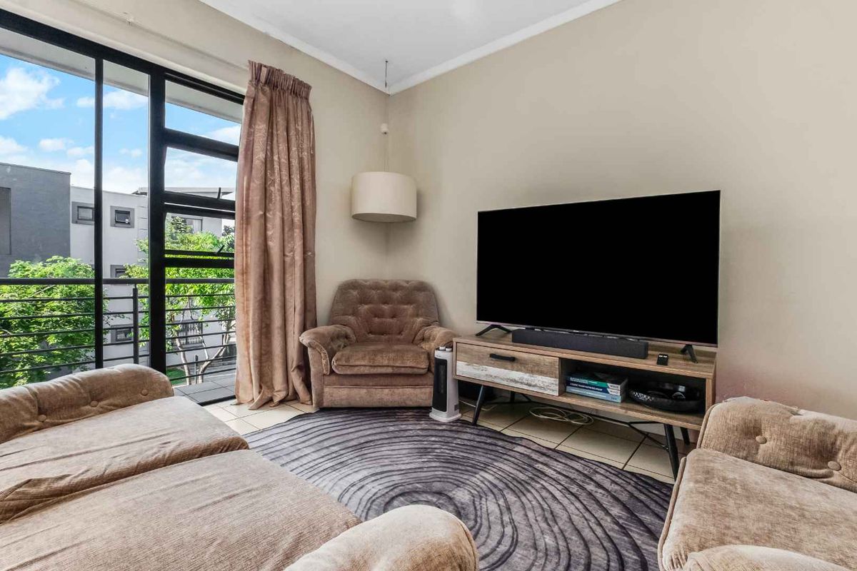 A comfortable living room featuring tiled flooring and a large sliding glass door that provides access to an outdoor balcony area.