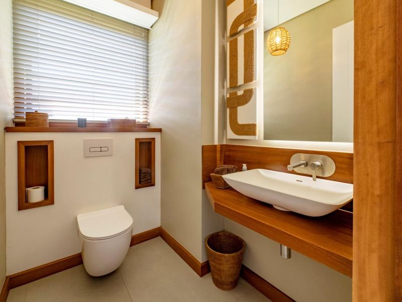 Modern guest bathroom featuring a wall-mounted toilet, floating timber vanity with a vessel sink, and integrated wall niches.
